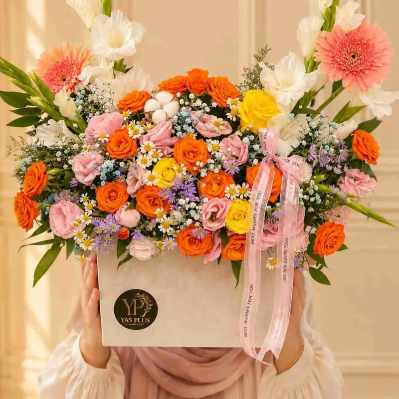 باکس گل رنگارنگ لوکس با رزهای نارنجی، صورتی و زرد، ژربرا، گل‌های سفید و بنفش و روبان صورتی