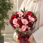 دسته گل رز قرمز و صورتی فلورا با گل‌های زرشکی، برگ سبز و روبان زرشکی