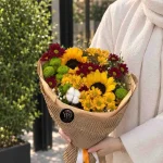 دسته گل آفتابگردان و داوودی آفتاب پاییزی با گل‌های زرد و زرشکی و کاغذپیچ کاهی